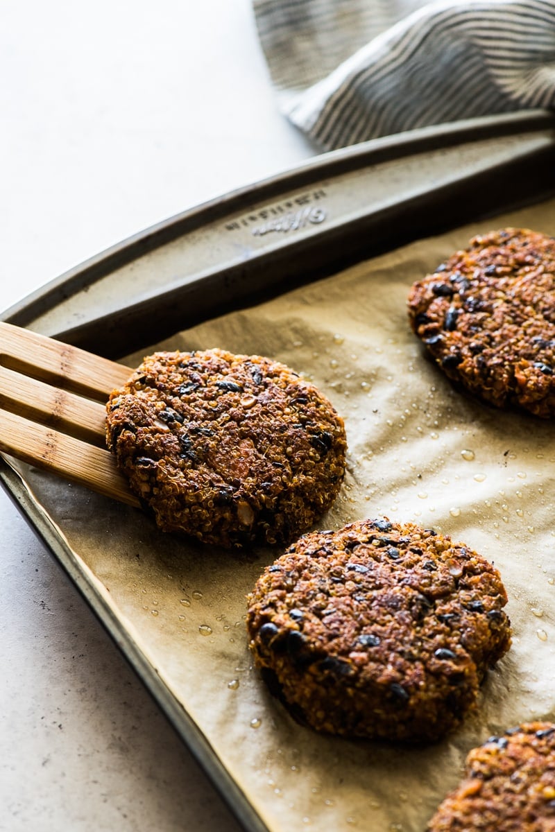 Cooked black bean burgers on a baking sheet lined with brown parchment paper.