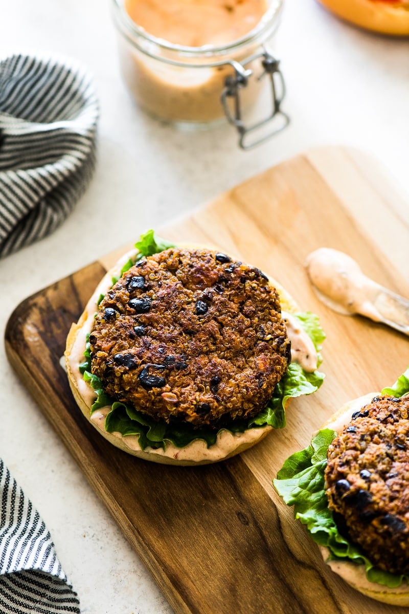 A black bean burger patty on top of green leaf lettuce and a bun.