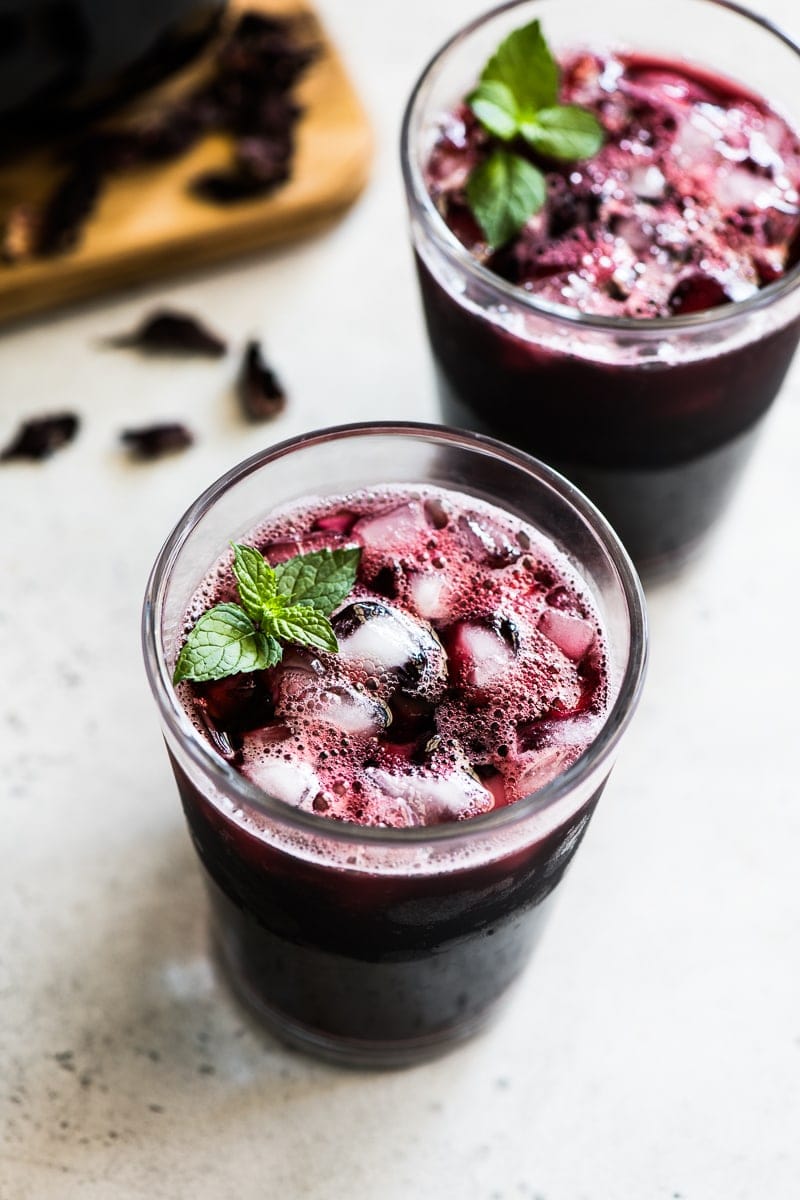 A glass of Agua de Jamaica filled with ice and garnished with fresh mint leaves.