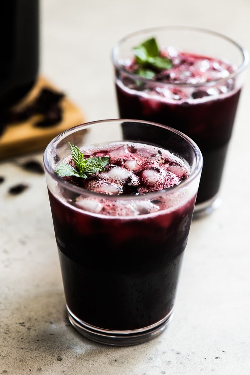 A glass filled with Agua de Jamaica and garnished with mint leaves.