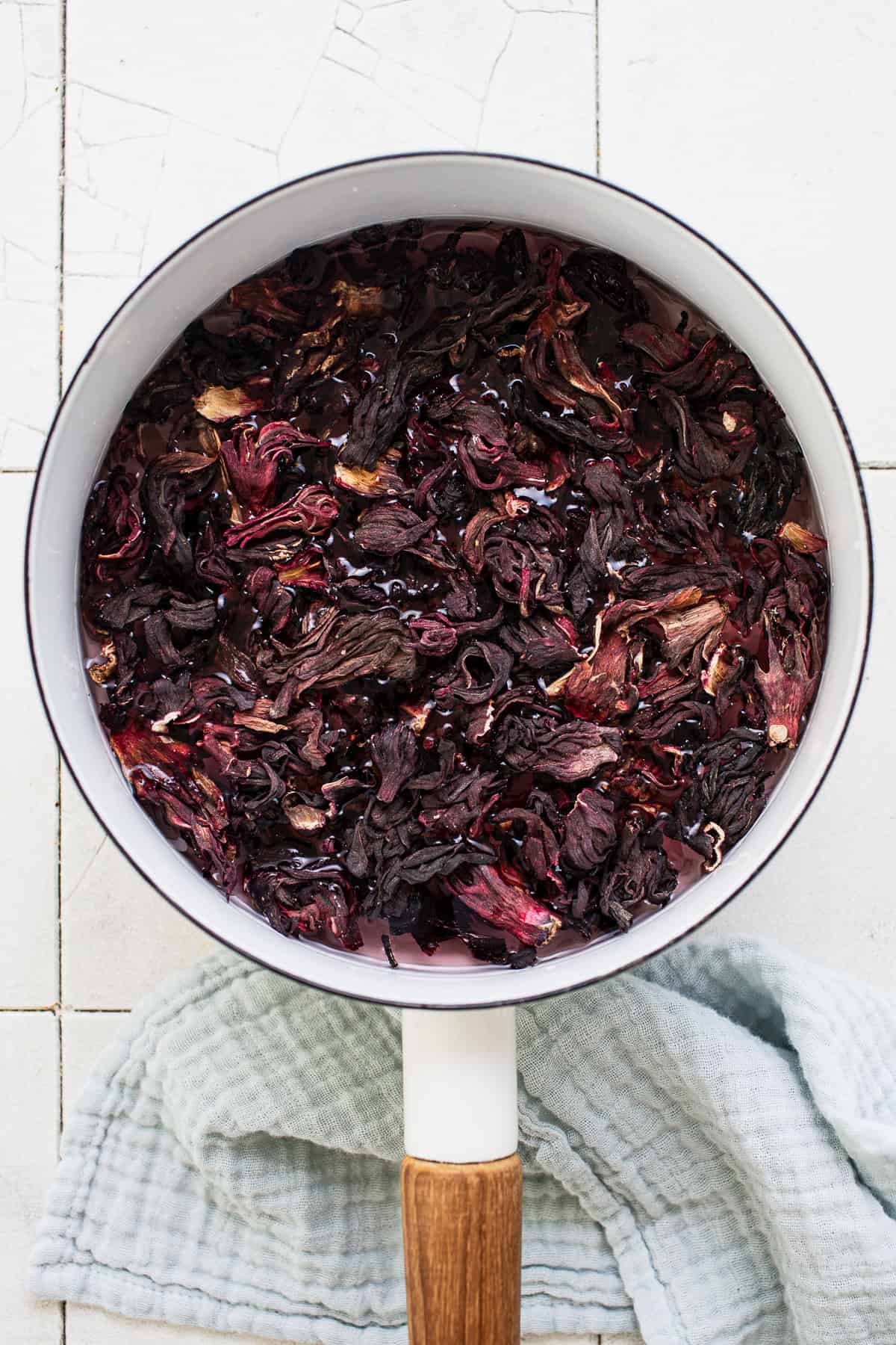 Dried hibiscus flowers simmering in a pot.