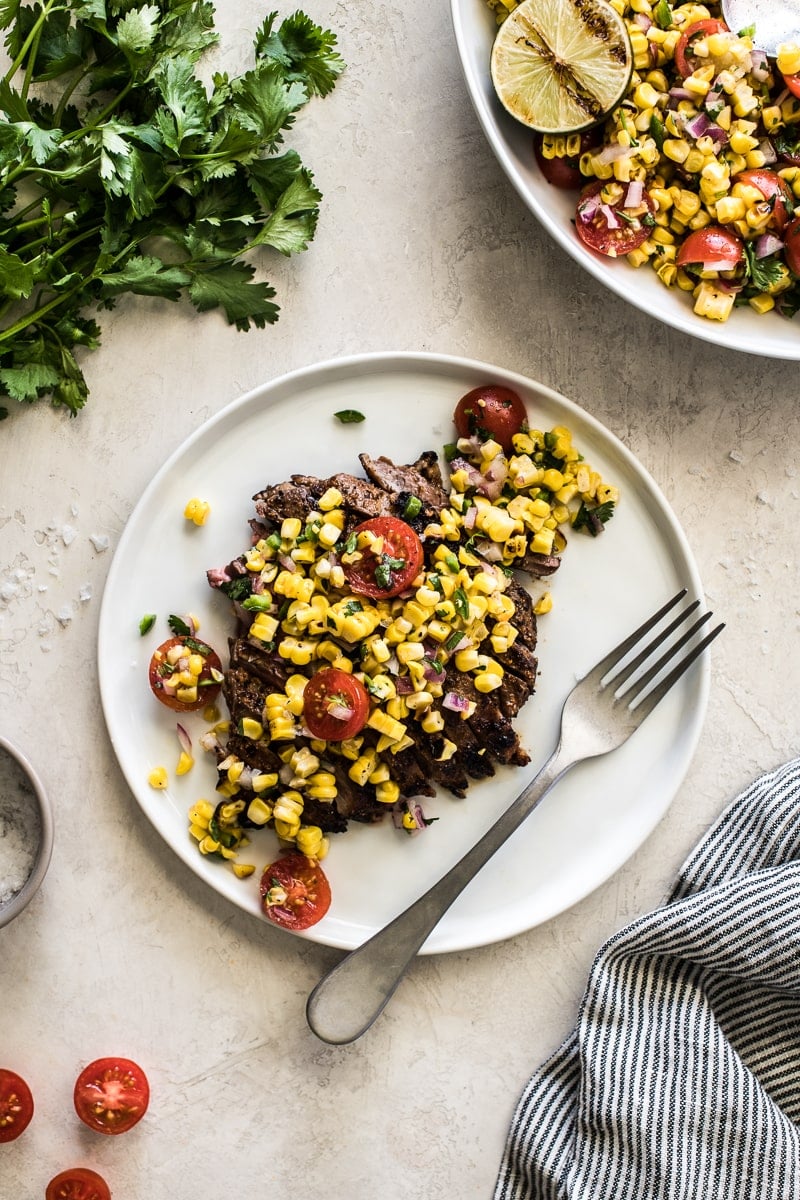 Grilled steak on a white plate topped with grilled corn salsa.