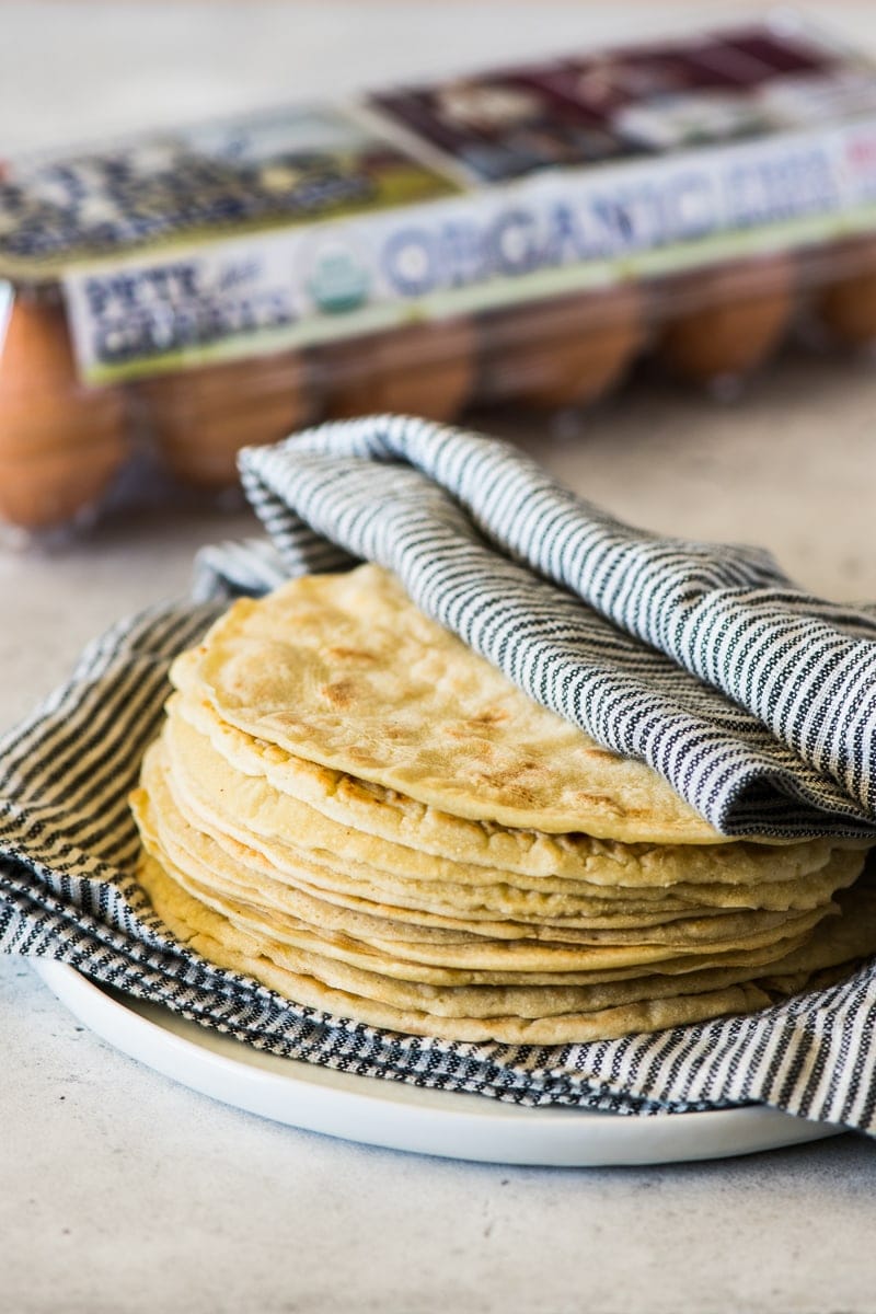 A stack of paleo tortillas covered with a clean kitchen towel.