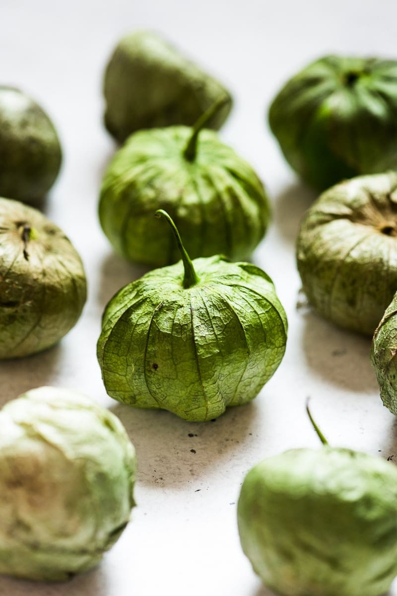 Tomatillos with their paper husk on a table.