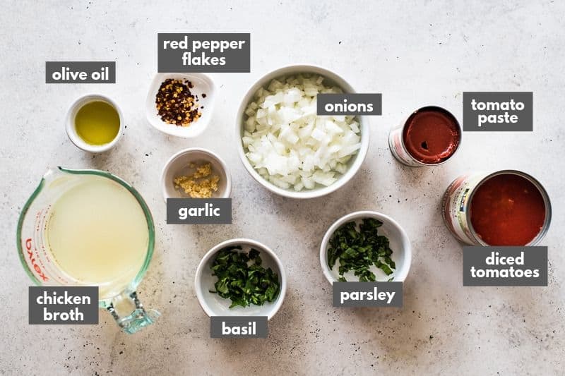 Arrabiata sauce ingredients on a table including canned diced tomatoes and red pepper flakes.