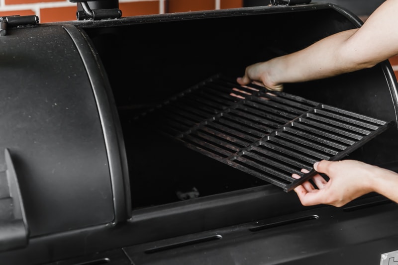 Hands removing grill grates from a grill.
