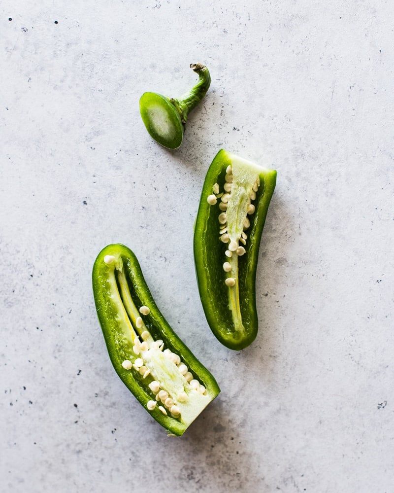 A jalapeno pepper sliced open in half revealing the inside veins and seeds.