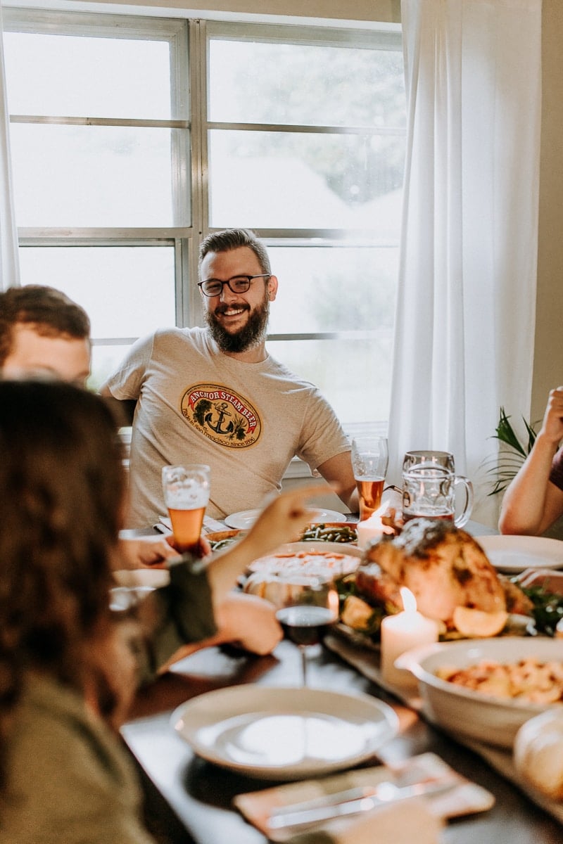 A group of people enjoying themselves at a table set for a Friendsgiving celebration.