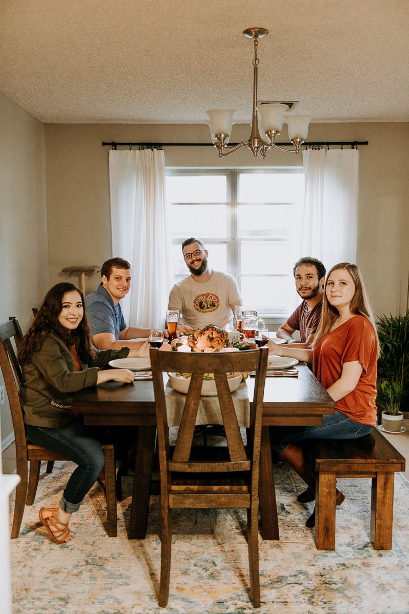 Friends smiling around the dinner table for Friendsgiving