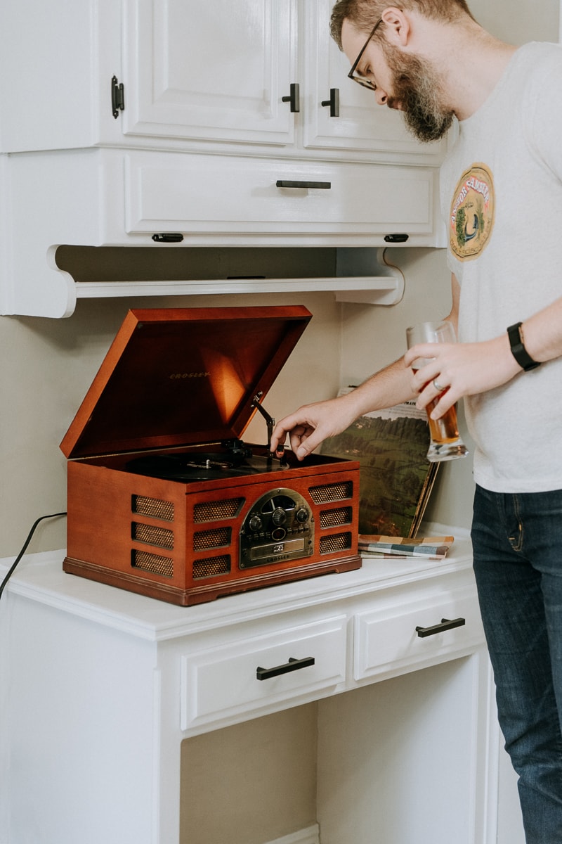 A man putting a record on the record player for Friendsgiving.