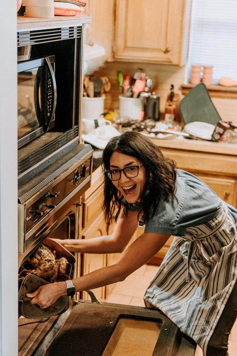 Isabel of Isabel Eats taking out the Friendsgiving turkey from the oven.