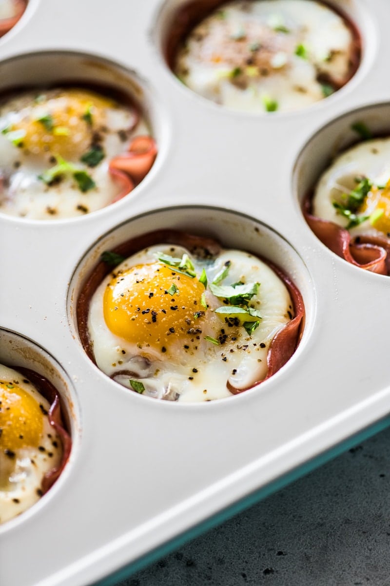 Baked eggs in a muffin tin with ham, roasted poblanos, and topped with chopped cilantro.