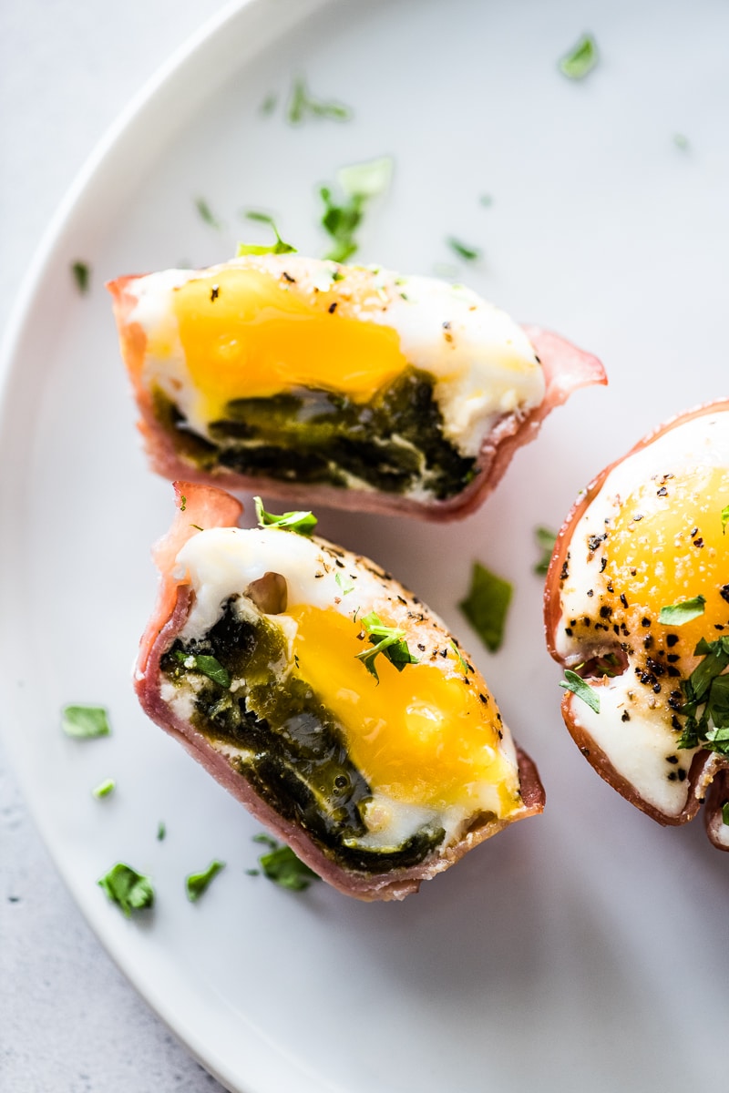 A baked egg sliced in half to show a layer of ham, roasted poblanos and eggs.