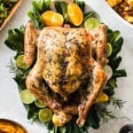 Herb Roast Turkey on a large platter next to Thanksgiving side dishes.