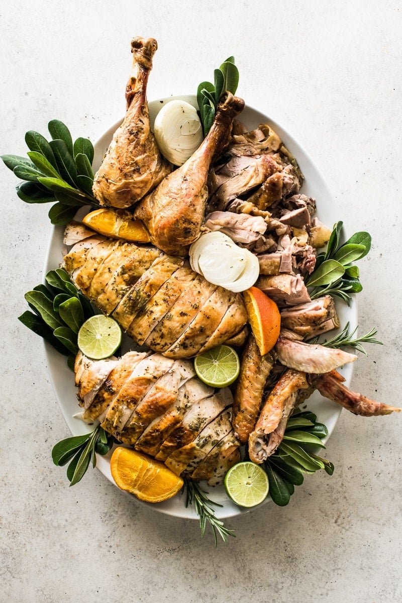 A carved turkey on a large platter decorated with greenery.