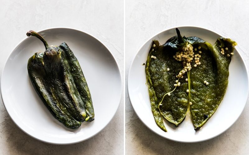 A roasted poblano pepper on a plate sliced open to reveal the seeds.