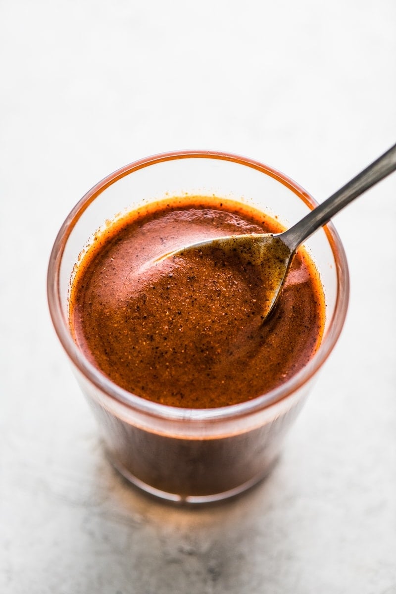 Easy enchilada sauce in a jar with a spoon.