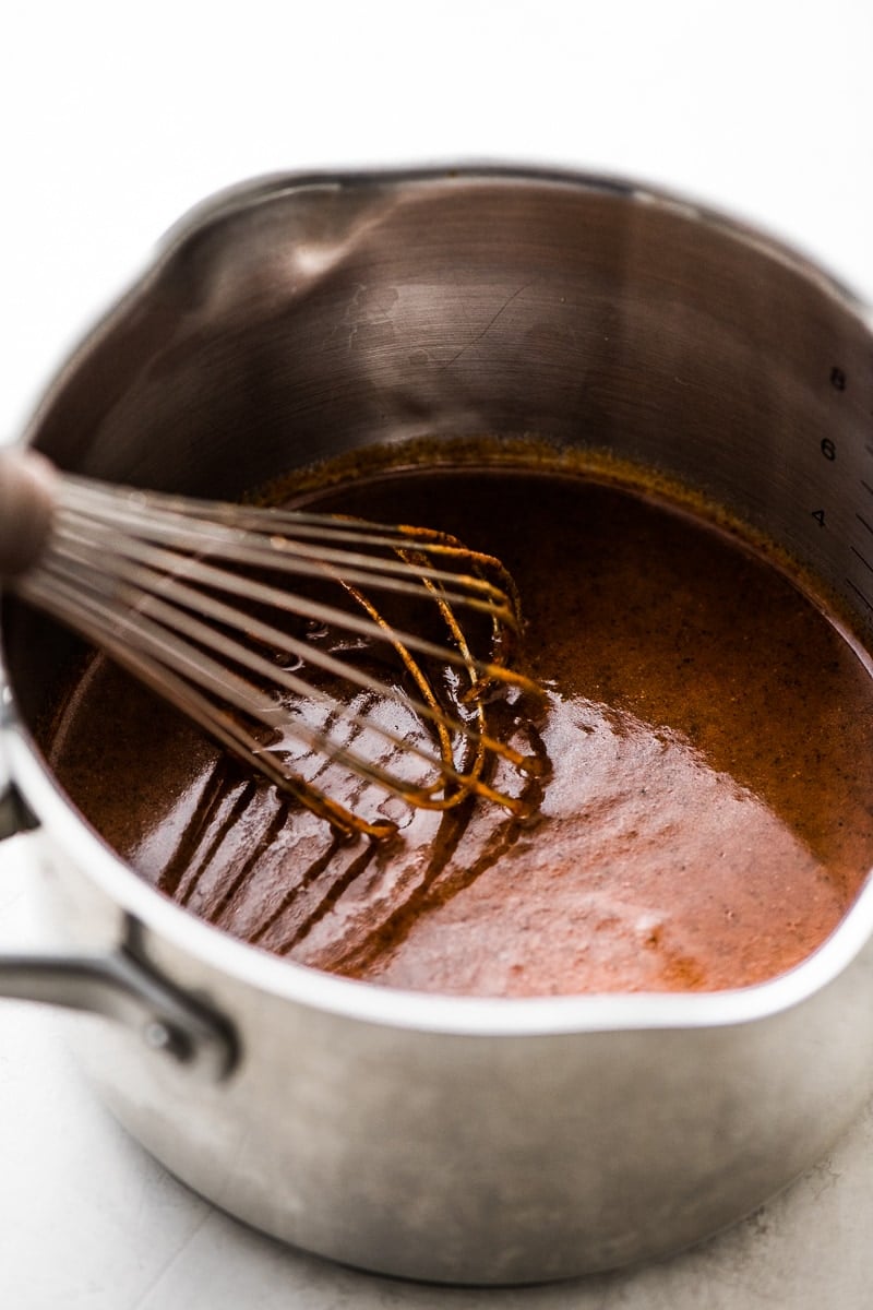 10-minute enchilada sauce in a pot with a whisk.