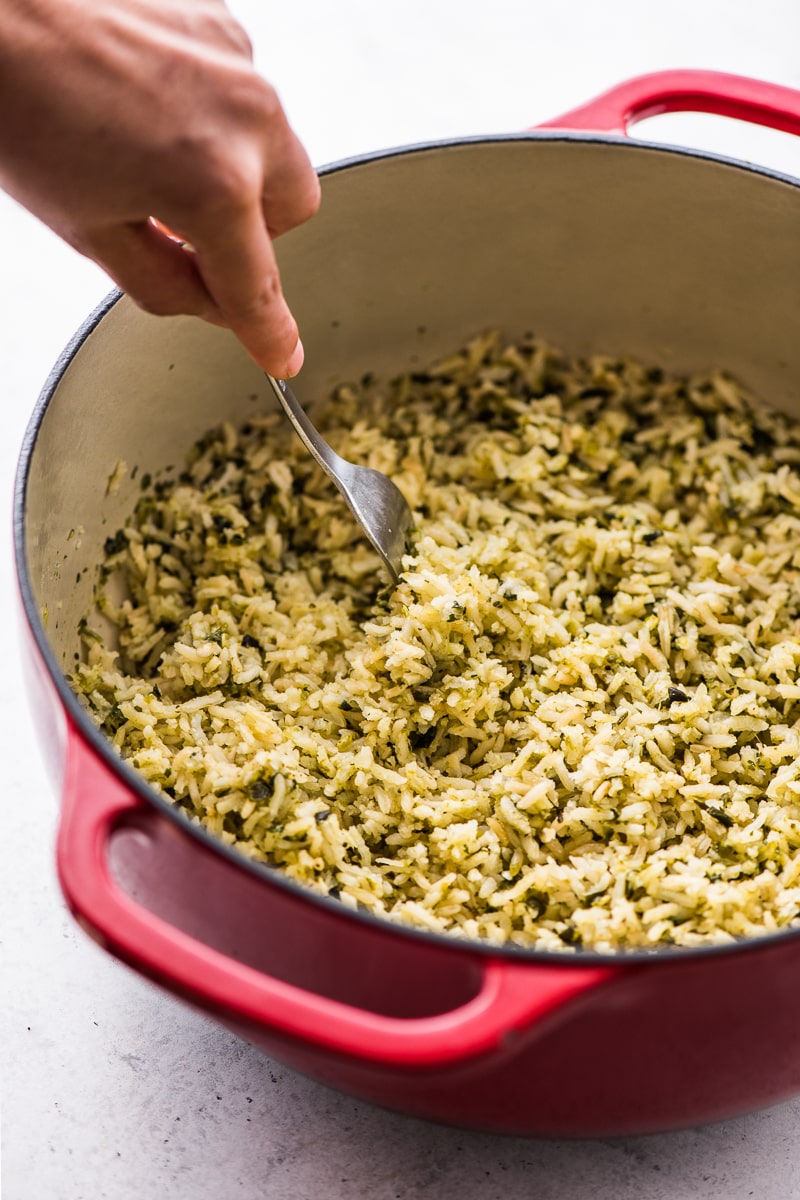 A fork fluffing some arroz verde (green rice).