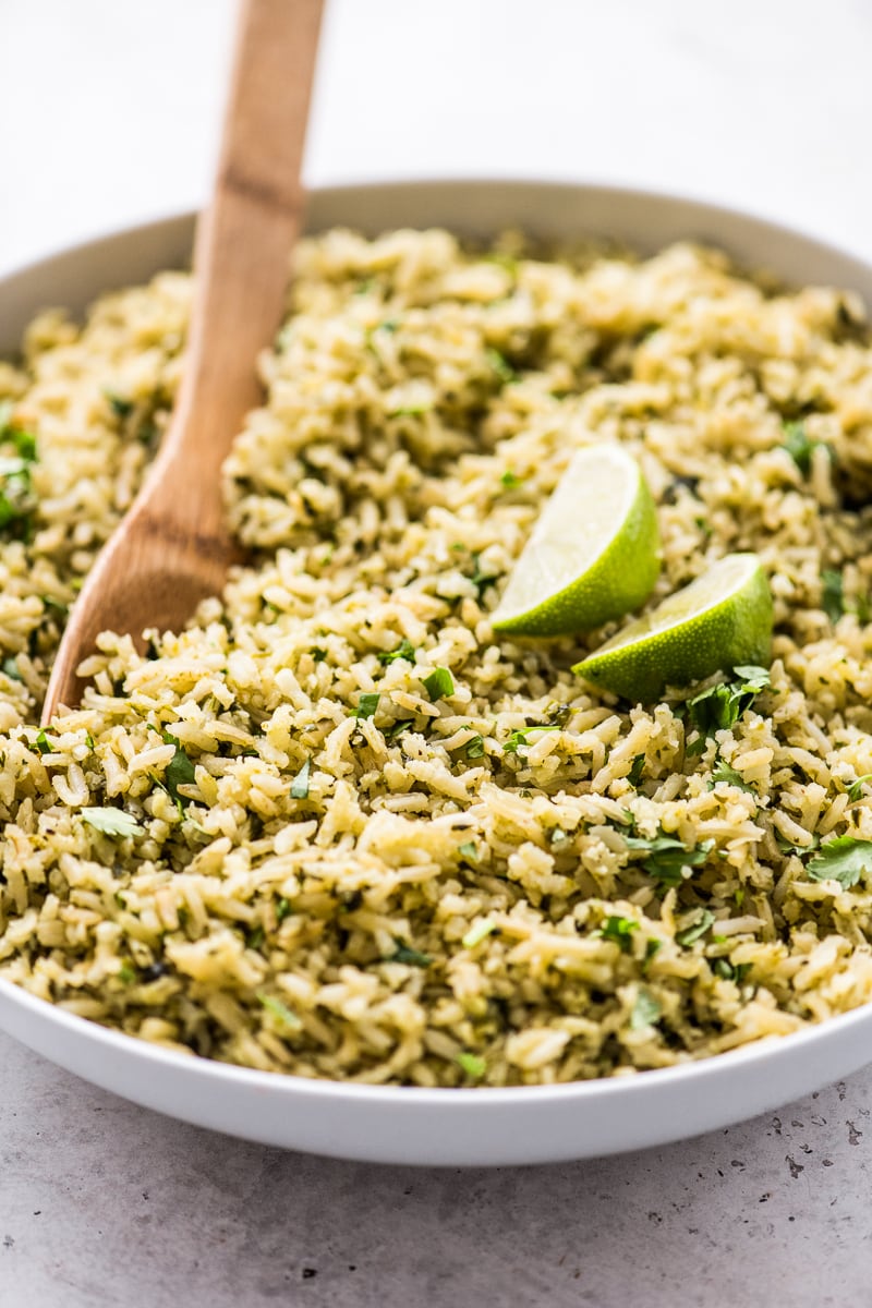 Arroz Verde in a white bowl topped with two lime wedges.