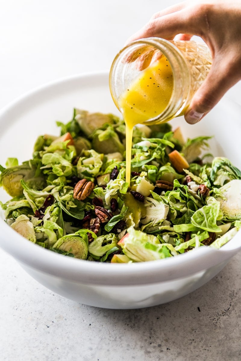 Pouring dressing on top of brussel sprout salad.