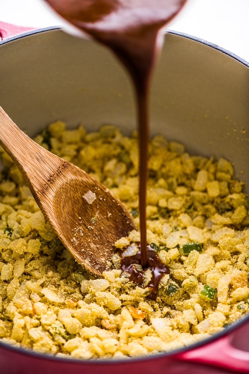 Pouring enchilada sauce into a pot for chicken enchilada soup.