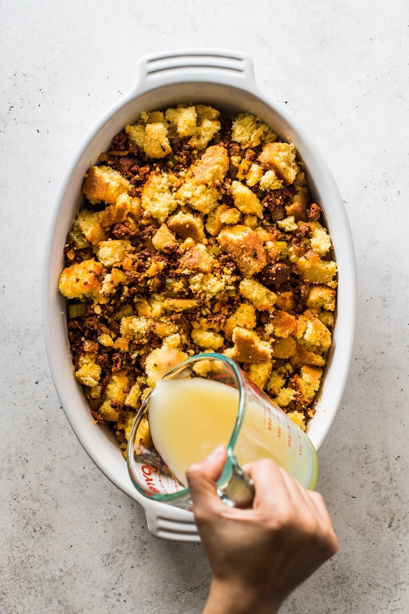 Broth being poured on top of cornbread stuffing.