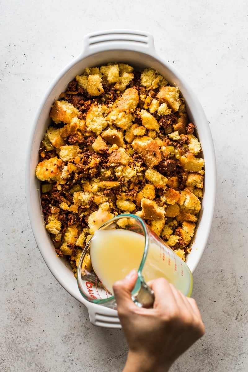 Broth being poured on top of chorizo cornbread stuffing.