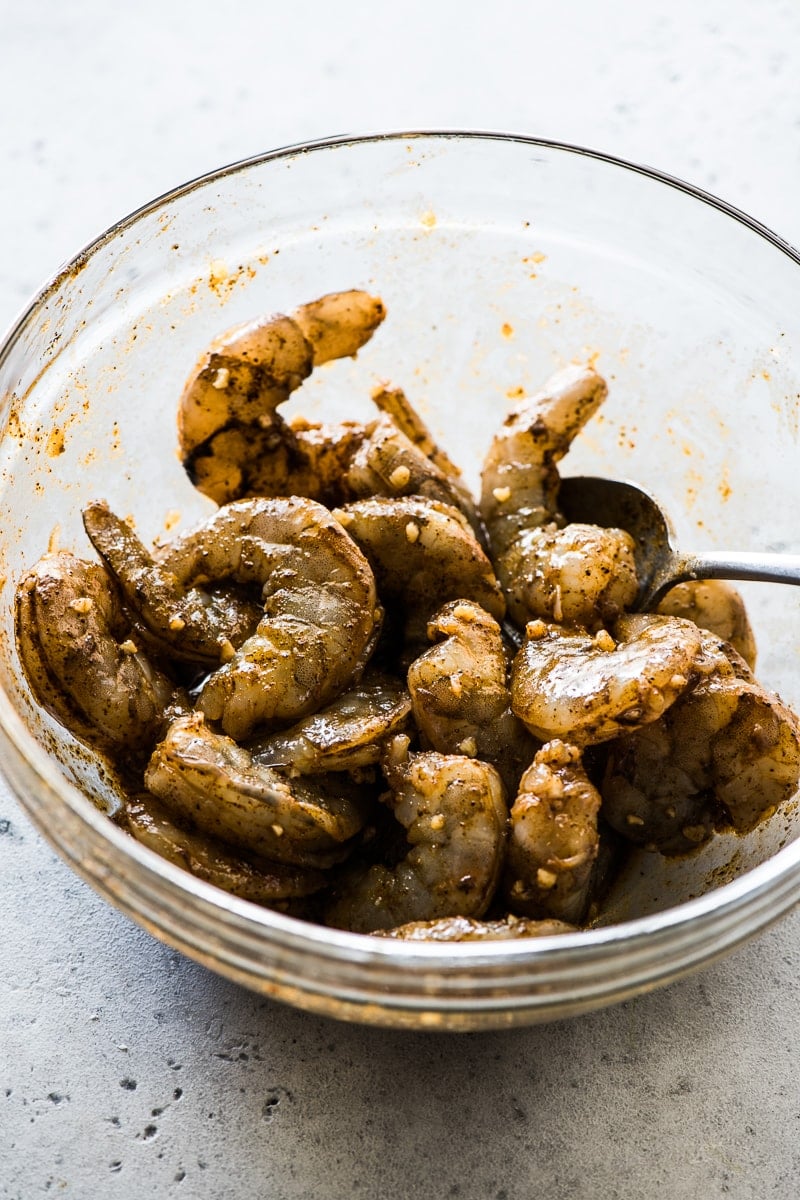 Seasoned and marinaded shrimp in a glass bowl.