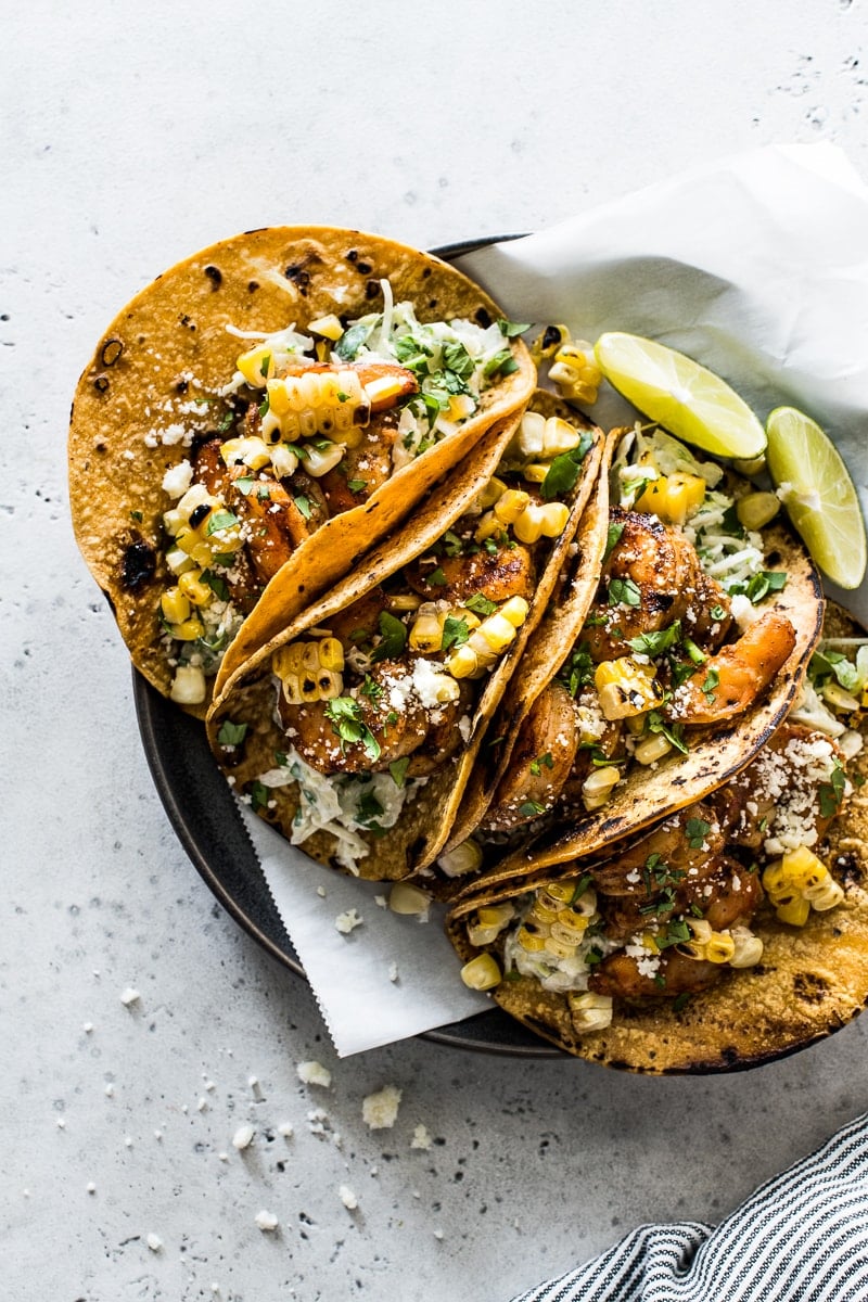 Grilled shrimp tacos on a plate topped with cotija cheese and cilantro.