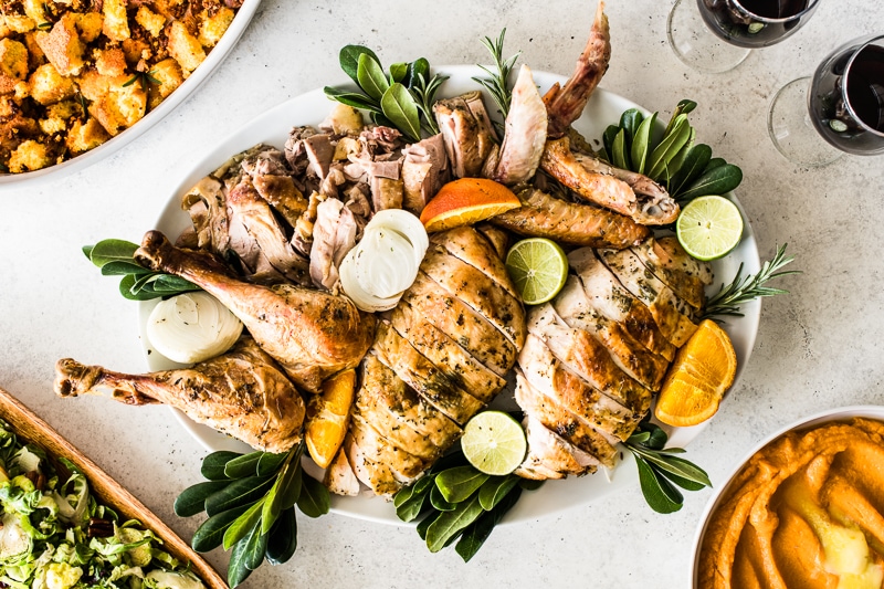 A carved turkey on a platter surrounded by Thanksgiving side dishes.