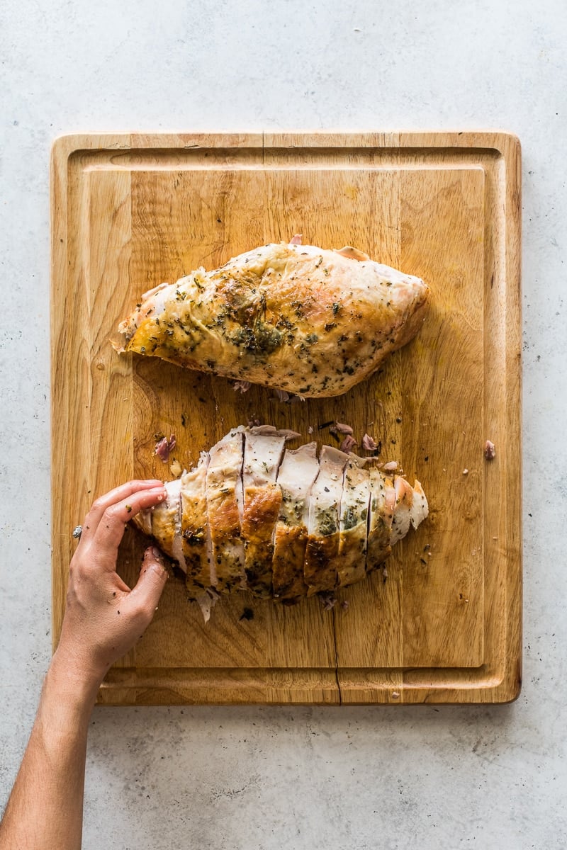 Two large turkey breasts sliced on a cutting board.