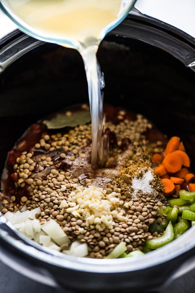 Broth being poured into a crockpot lentil soup