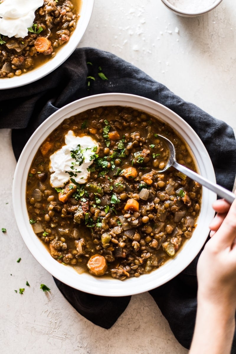 Crockpot lentil soup topped with sour cream and cilantro