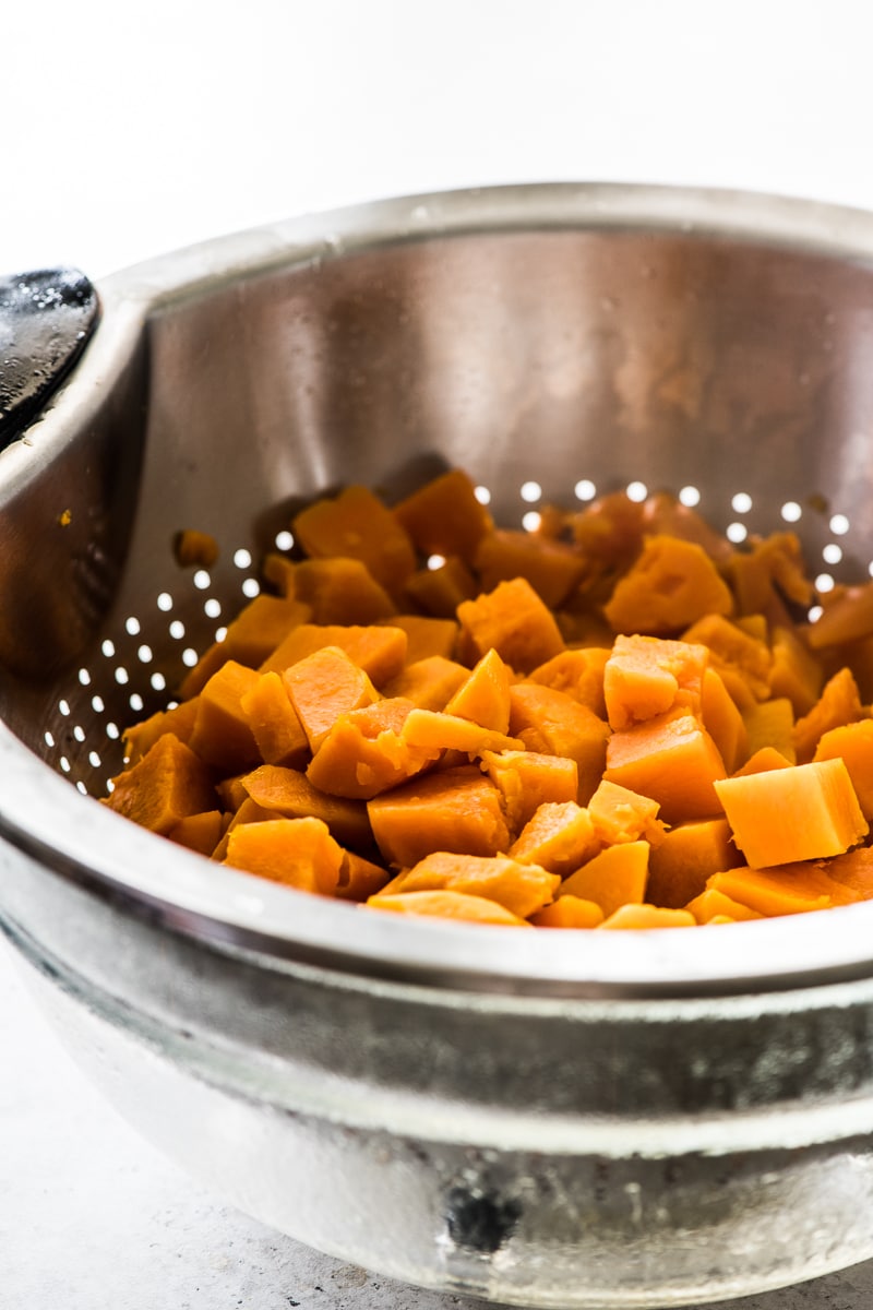 Cooked and diced sweet potatoes in a strainer.