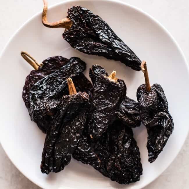 Dried ancho chile peppers on a white plate