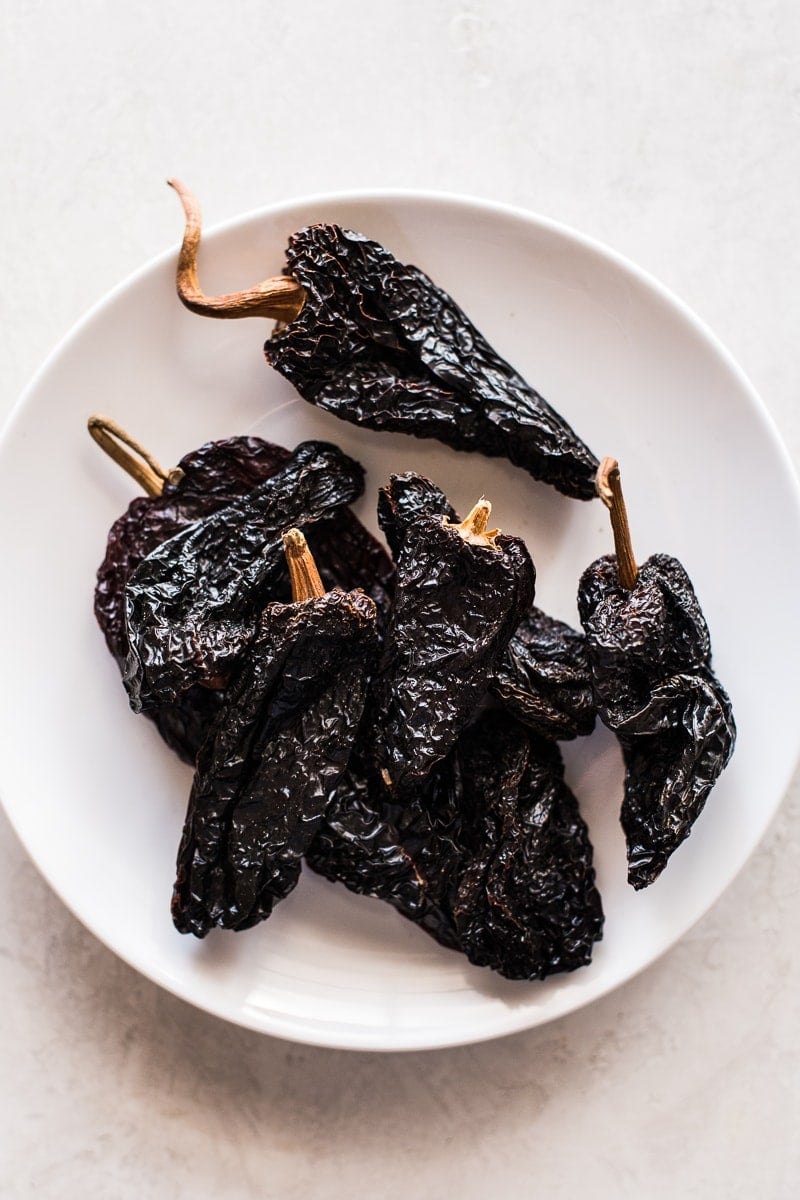 Dried ancho chile peppers on a white plate