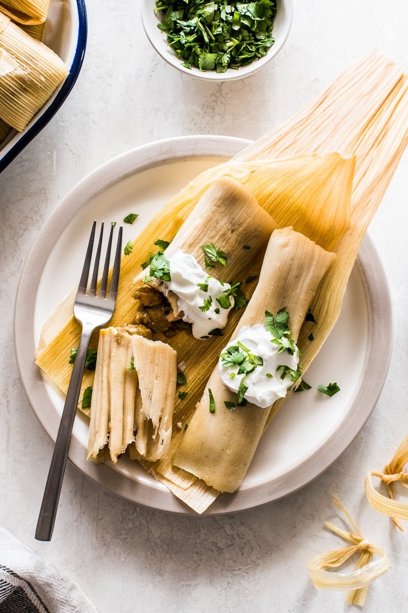 Chicken tamales made from an easy masa tamale dough and stuffed with tender pieces of chicken and green chile verde sauce. Great for serving a crowd or freezing and reheating for later! #tamales #chickentamales #glutenfree #mexicanfood