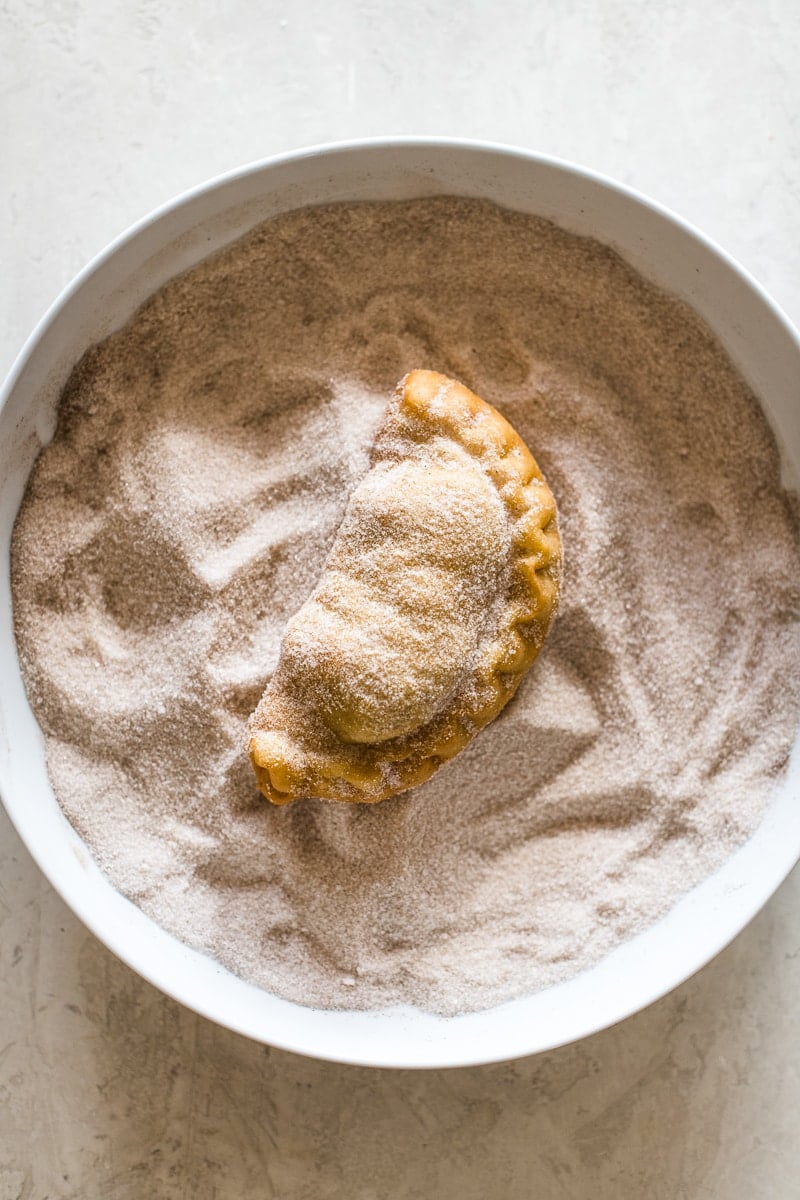 An empanada in a bowl with cinnamon sugar