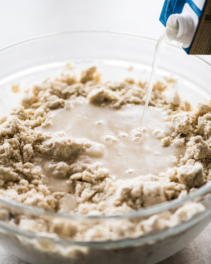 Broth being poured into a bowl of masa for tamales