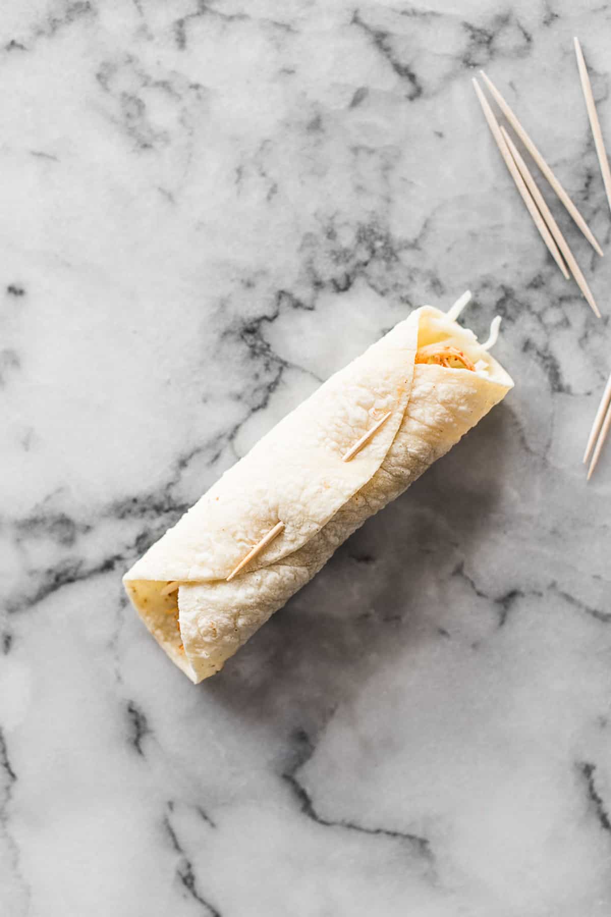 A rolled corn tortilla secured shut with a toothpick.