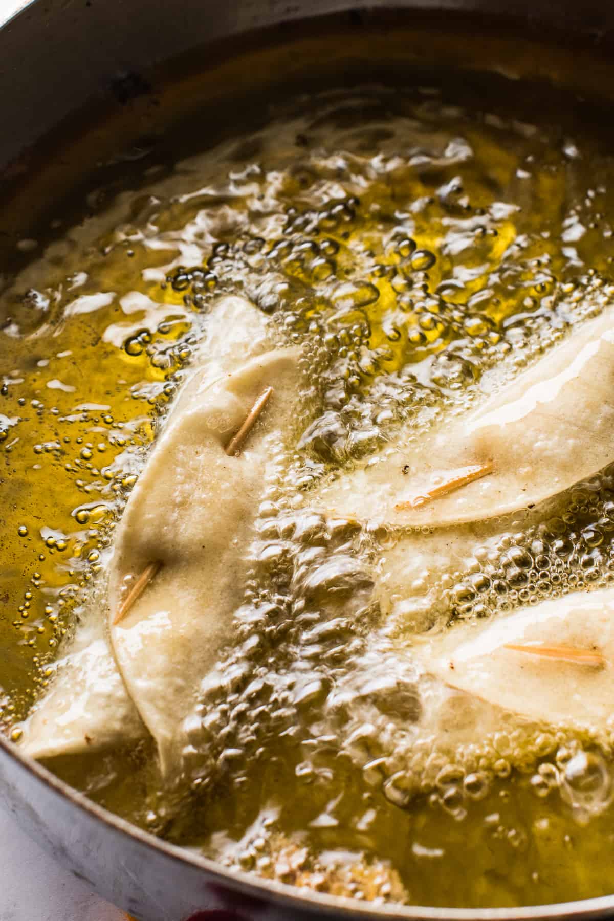 Chicken taquitos frying in oil
