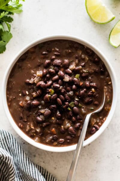 how-to-cook-canned-black-beans-small-2 Cooked canned black beans with tomatoes, onions and garlic in a bowl.