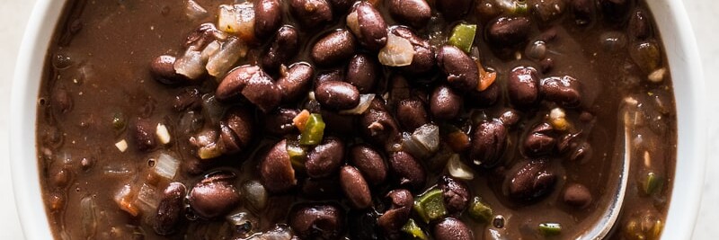 Cooked canned black beans with tomatoes, onions and garlic in a bowl.