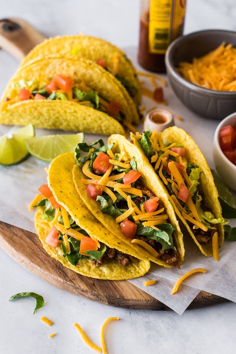 Hard shell tacos topped with lettuce, cheese and tomatoes.