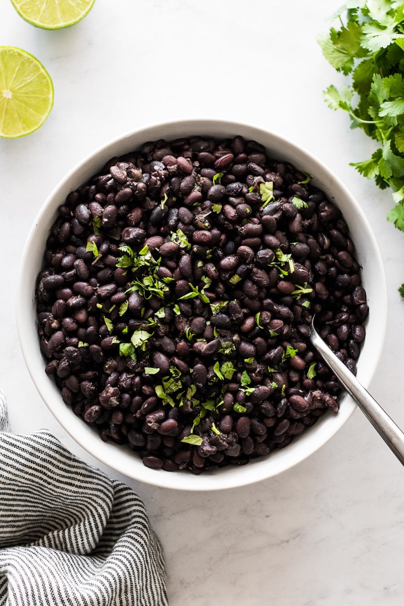 Cooked black beans topped with cilantro in a bowl.