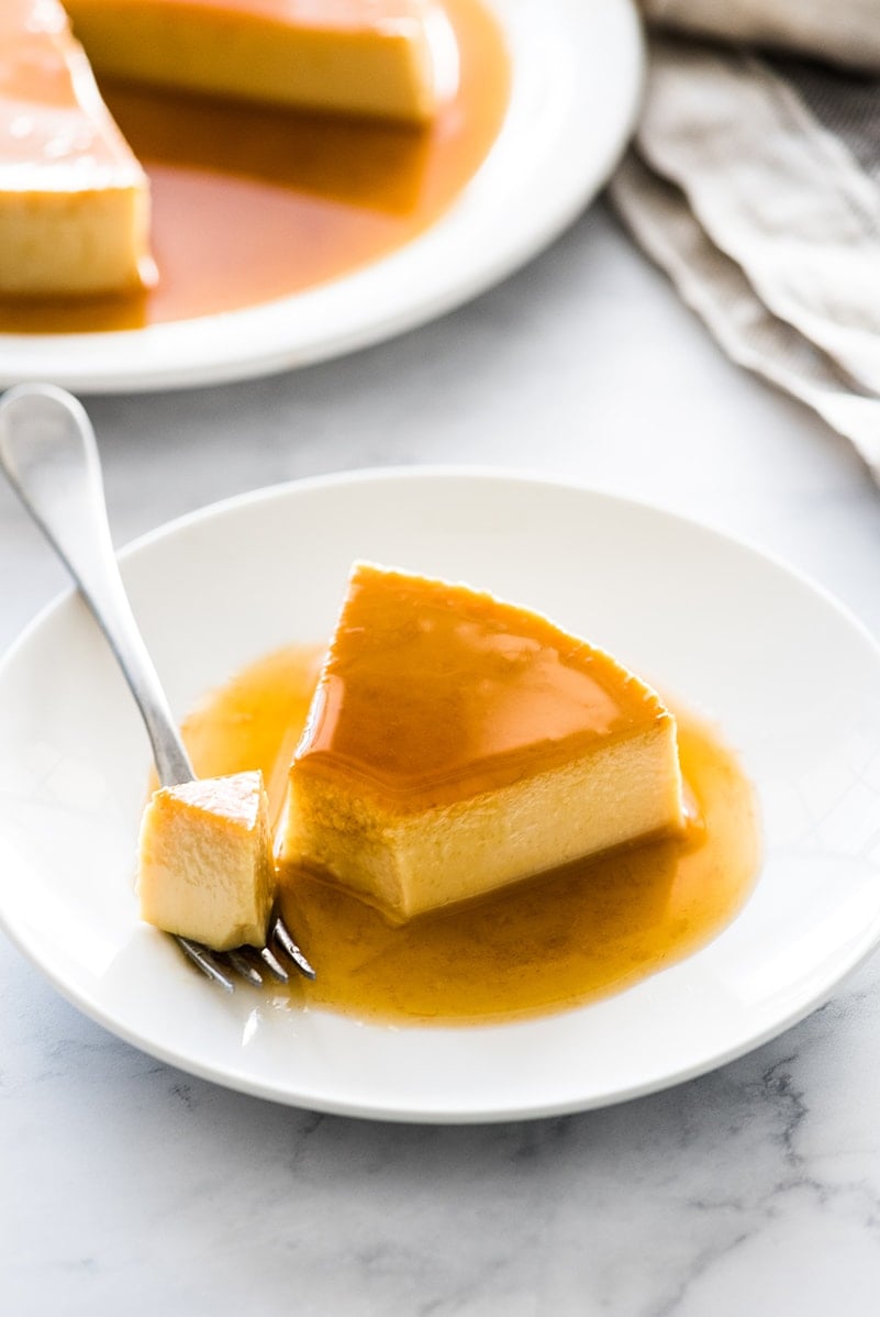 A slice of flan on a plate with a fork