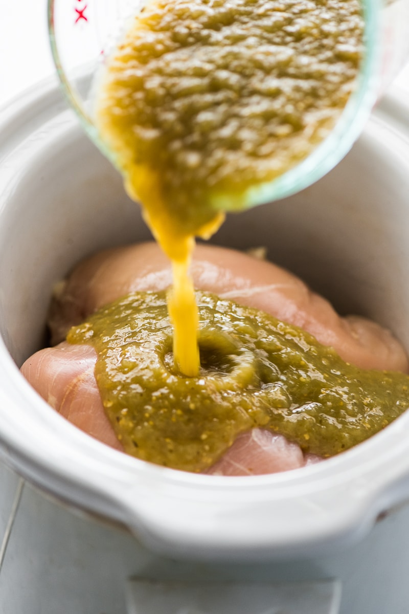 Salsa verde being poured onto chicken breasts