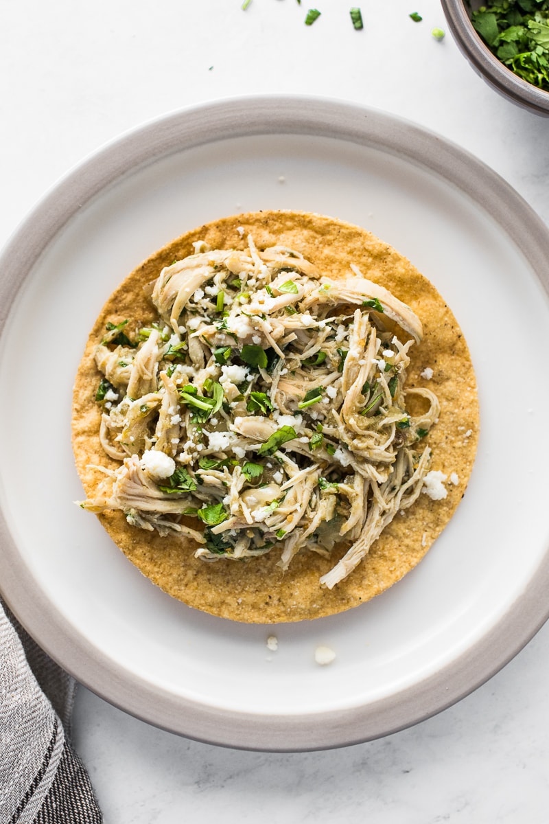 Salsa verde chicken on top of a tostada