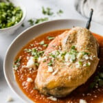 Chile relleno on a plate with red salsa.